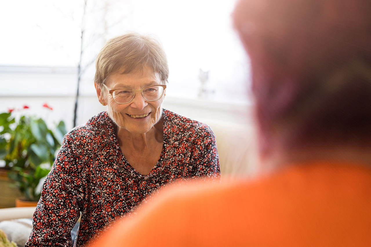 Lächelnde Seniorin unterhält sich mit Pflegerin